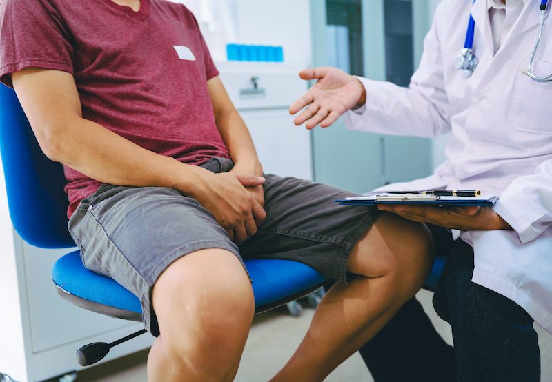 man sitting with discomfort at doctor's office